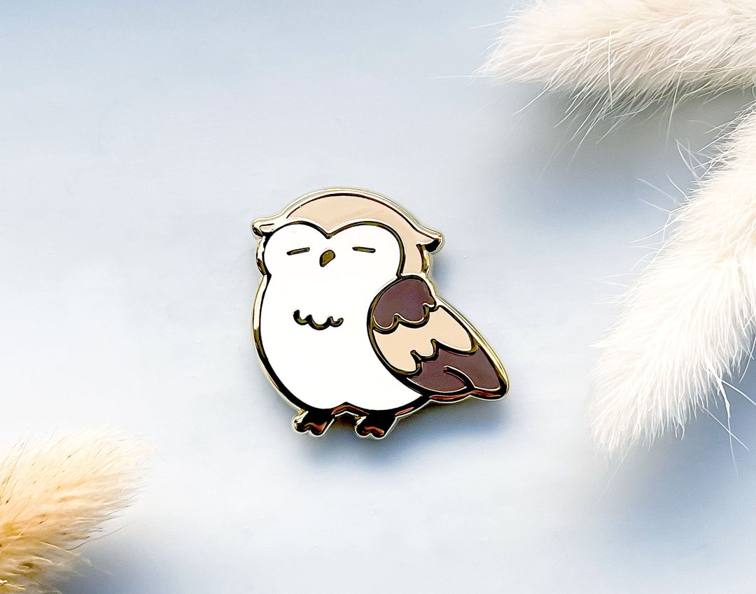 Owl-shaped needle minder magnet on a soft, fluffy background.