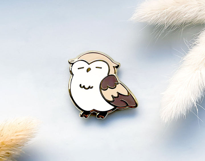 Owl-shaped needle minder magnet on a soft, fluffy background.